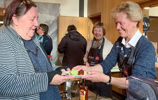 Eine Frau schenkt einer anderen Frau eine warme Mahlzeit aus.
