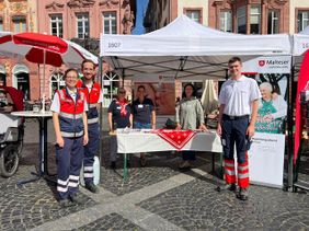 Auf dem Foto sind mehre Personen der Malteser zu erkennen an einem Informationsstand der Malteser. 