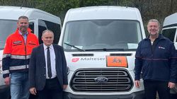 Drei Männer stehen vor mehreren Kleinbussen der Malteser.