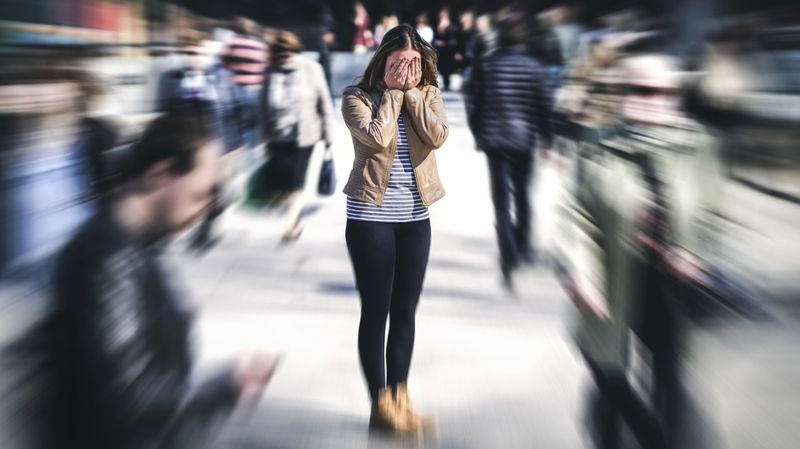 Eine junge Frau hält sich in einer Menschenmenge die Augen zu