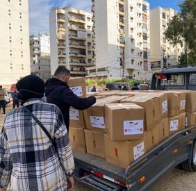 Ein Anhänger mit Hilspaktenen wird entladen.