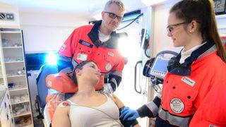 Malteser Mitarbeiter versorgen eine Frau im Rettungswagen.