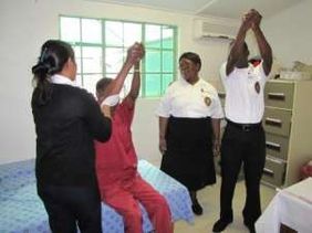 A man practices physiotherapy exercises with support from the care team.