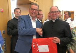 Zu sehen ist Martin Rösler (links) wie er dem neben ihm stehenden Wolfgang Rick die Hand zur Gratulation schüttelt. Beide blicken in die Kamera. 