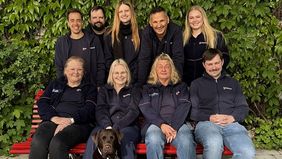 Gruppenfoto von neun Personen und einem Hund.