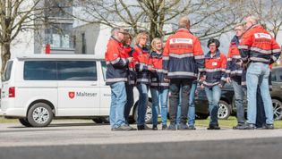 Mehrere Helferinnen und Helfer des PSNV-Teams beraten sich. Im Hintergrund ist ein Fahrzeug (Bulli) des PSNV-Teams zu sehen.