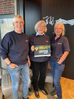 Drei Ehrenamtliche des Malteser Kulturbegleitdienstes präsentieren den symbolischen Scheck.