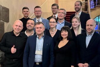 Mehrere Personen in Anzug und Festkleidung stehen auf einer Treppe