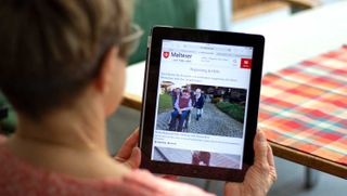 Frau schaut sich das Online-Magazin "dabei" auf einem Tablet an.