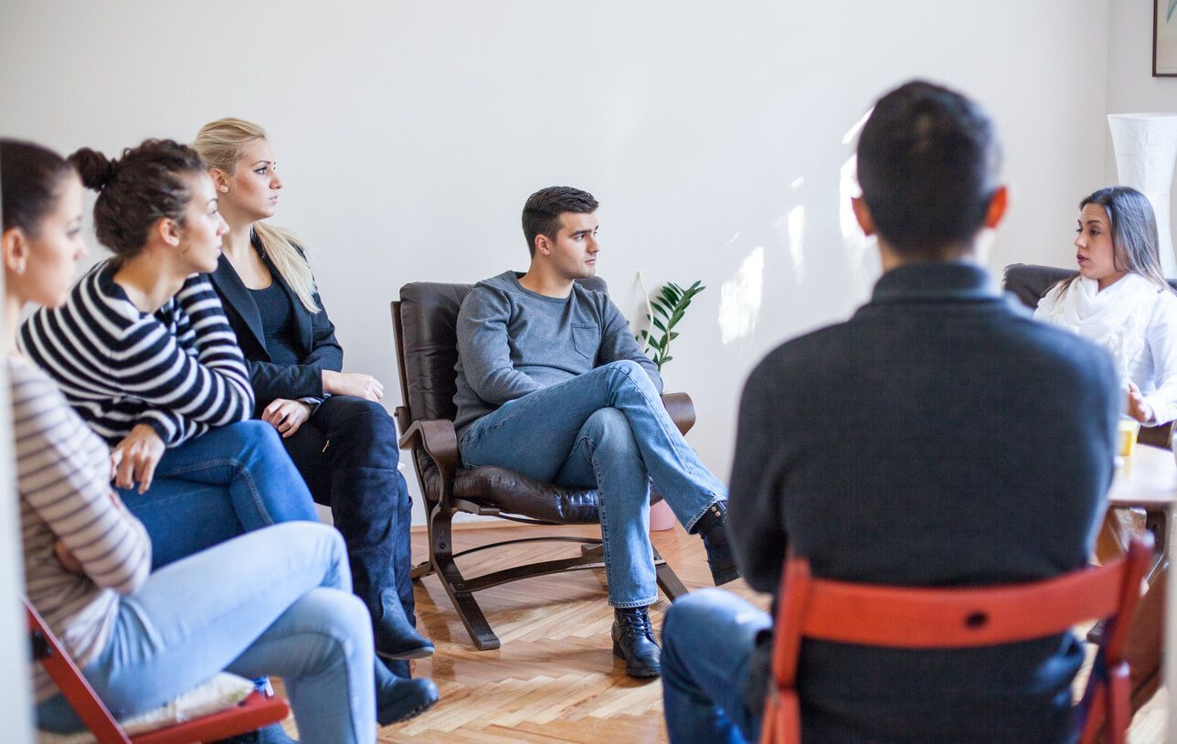 Junge Menschen sitzen in der Gruppe und besprechen sich