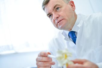 Ärztliche Fachkraft erläutert ein Wirbelsäulenmodell im Beratungsgespräch, helles Licht im Hintergrund.