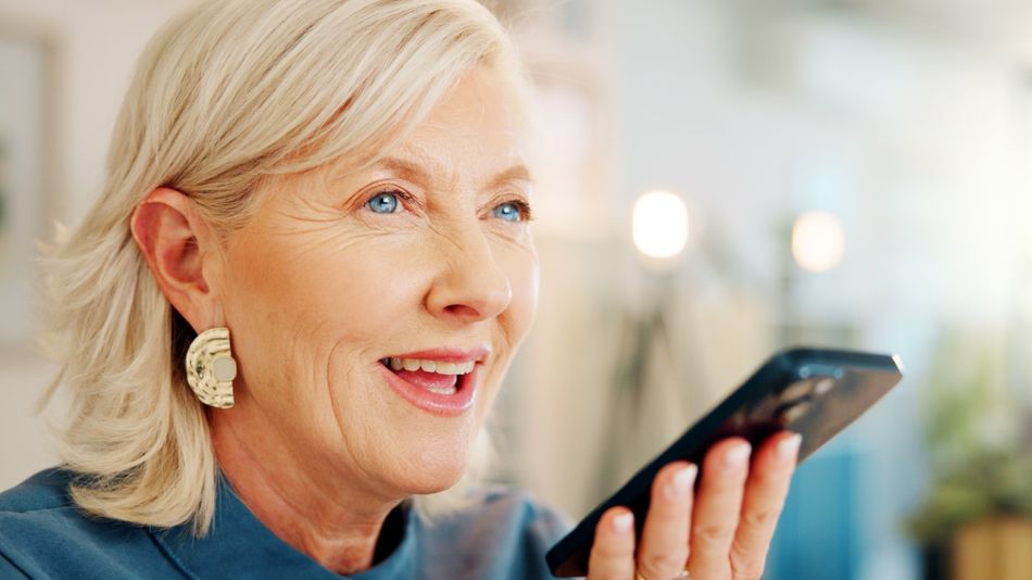 Eine ältere Frau spricht etwas in ein Smartphone.