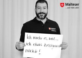 Lotse der Malteser hält ein Schild mit dem Satz "Ich mache es, weil ich etwas zurückgeben möchte!"