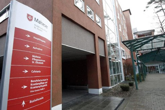 Eingang des Malteser Waldkrankenhaus St. Marien mit rotem Wegweiser und überdachtem Zugang.