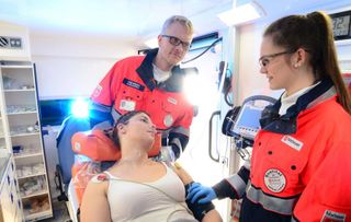 Malteser Mitarbeiter versorgen eine Frau im Rettungswagen.