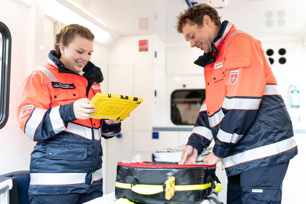 Es werden Malteser Notfallsanitäter im Rettungsdienstwagen gezeigt.