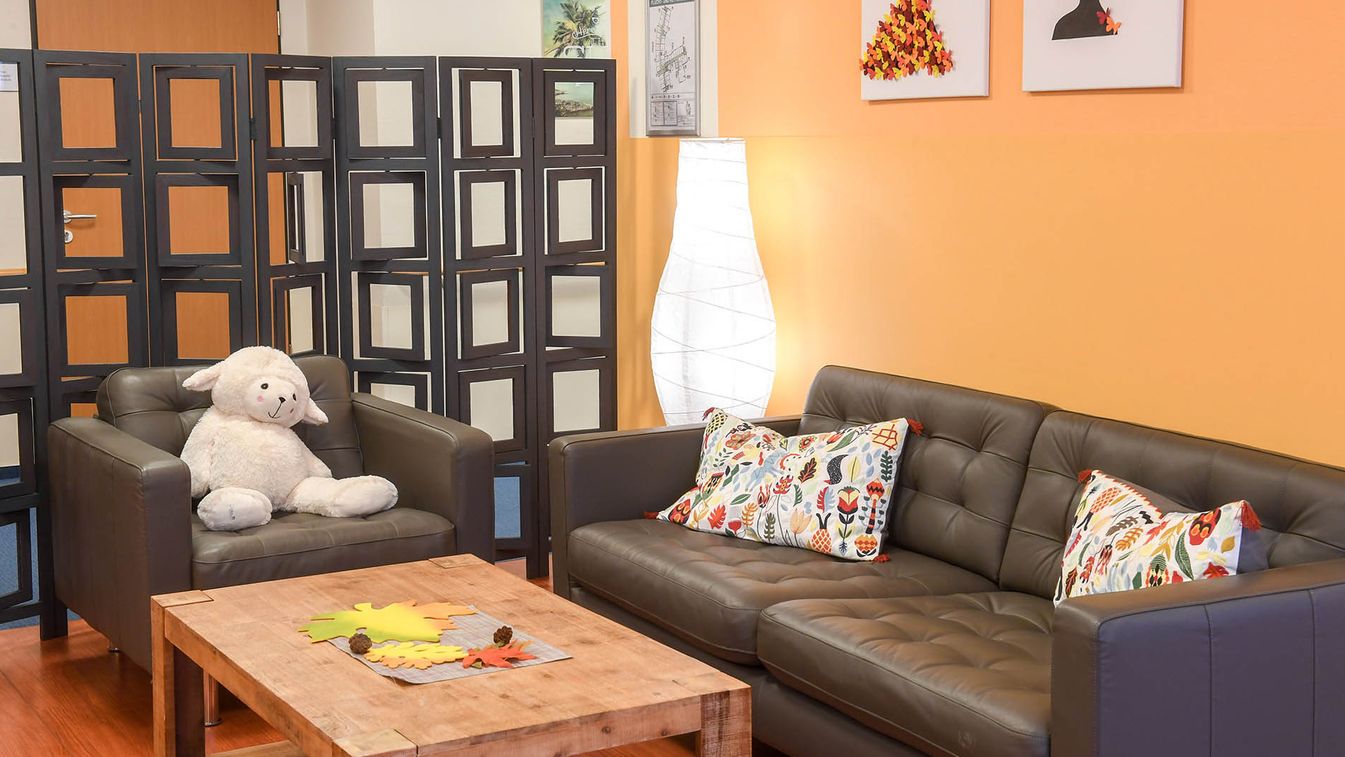 Ein Aufenthaltsraum der Jungen Pflege mit Sofa, bunten Kissen, Tisch und Lampe