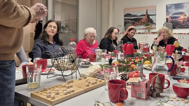 Mehrere Menschen sitzen um einen dekorierten Tisch und spielen Bingo