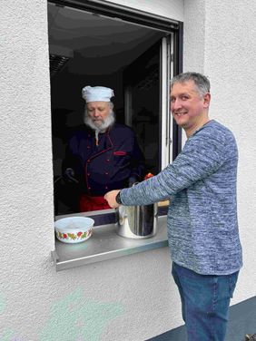 Ein Anwohner holt Erbsensuppe an einem Ausgabefenster ab