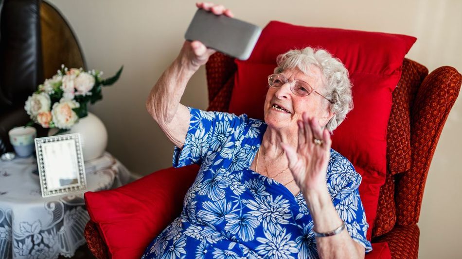 Eine lächelnde alte Frau mit einem Smartphone.
