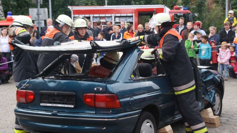 Angehörige einer Freiwilligen Feuerwehr entfernen das Dach eines Autos.