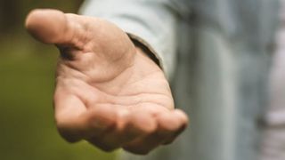 Großaufnahme einer Hand, die nach vorne ausgestreckt ist. 