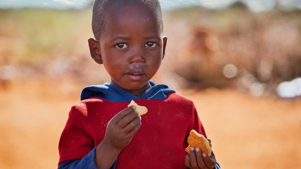 Es wird das Porträt eines afrikanischen Jungen gezeigt, welcher isst.