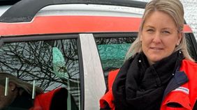 Eine Frau in Malteser Kleidung vor einem Malteser Dienstauto