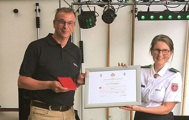 Der stellvertretende Diözesanleiter Matthias Geist (l.) nimmt die Verdiensturkunde und das Verdienstkreuz von Vizepräsidentin Clementine Perlitt entgegen (r.)