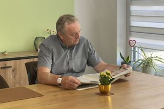 Ein Senior mit einem Hausnotruf-Armband beim Zeitunglesen