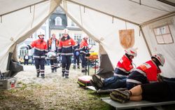 Einsatzkräfte tragen verletzte Personen in ein Behandlungszelt
