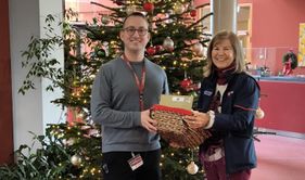 Eine Frau in Malteser Kleidung überreicht einem Mann eine Kiste mit Briefen