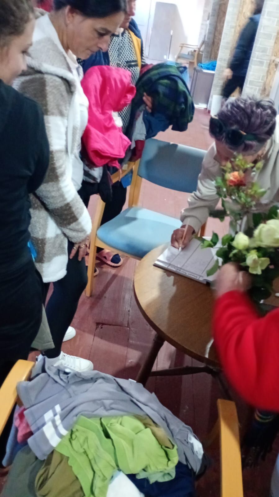 Eine Gruppe Menschen steht um eine Frau, die ausgegebene Spenden registriert.