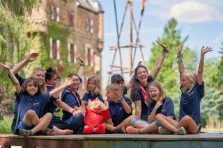 Eine Gruppe von Kindern und Jugendlichen sitzt in einer Runde. Alle Lachen und jubeln.
