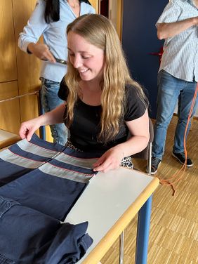 Eine Frau, lächeln und sitzend am Tisch, betrachtet eine alte Einsatzhose.