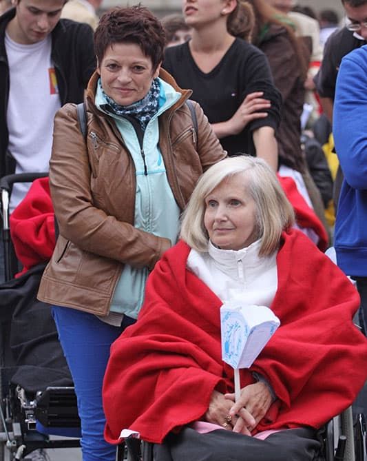 Bei einer Wallfahrt schiebt eine Frau einen Rollstuhl mit einer älteren Frau