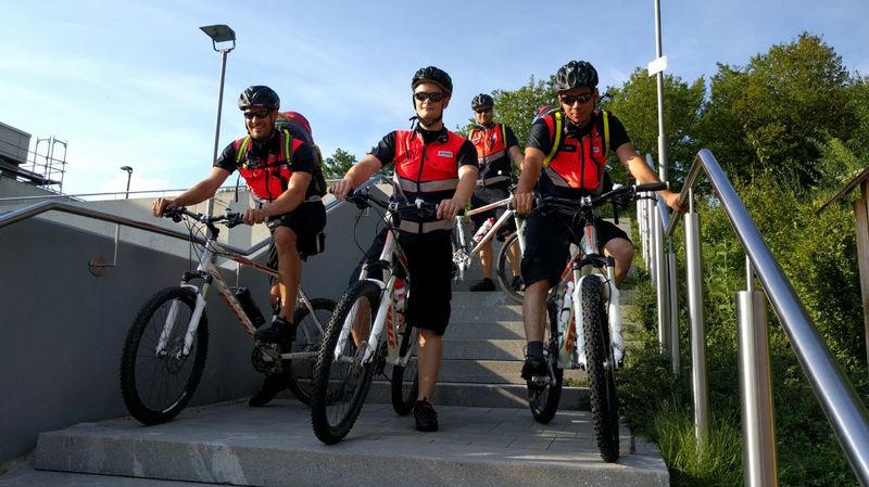 Vier Männer in Signalwesten auf Fahrrädern auf einer Betontreppe.