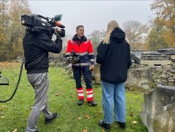 Auf dem Foto ist ein Kamerateam zu sehen, welches einen Helfender der Malteser Rettungshundestaffel interviewt.