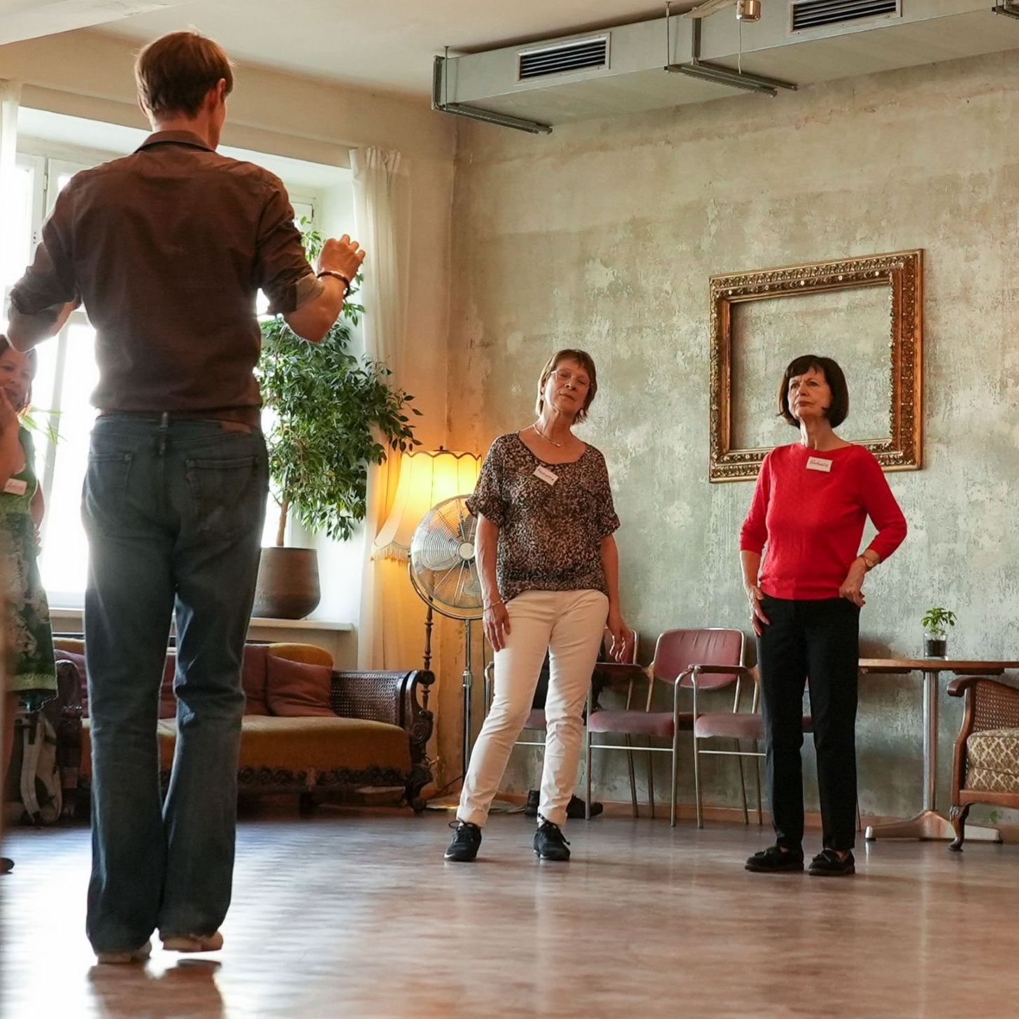 Gruppe bei einer Trauer- und Tango-Veranstaltung des Malteser Hilfsdienstes, Teilnehmer stehen im Kreis und hören einer Anleitung zu.