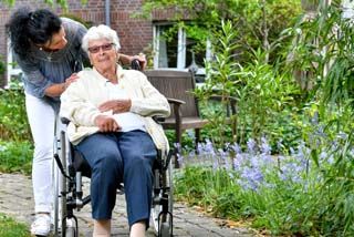 Pflegerin und Bewohnerin gehen spazieren 