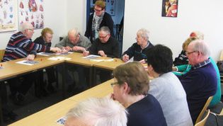 Mehrere Seniorinnen und Senioren spielen unter Anleitung Bingo in einem Raum der Lohner Malteser.