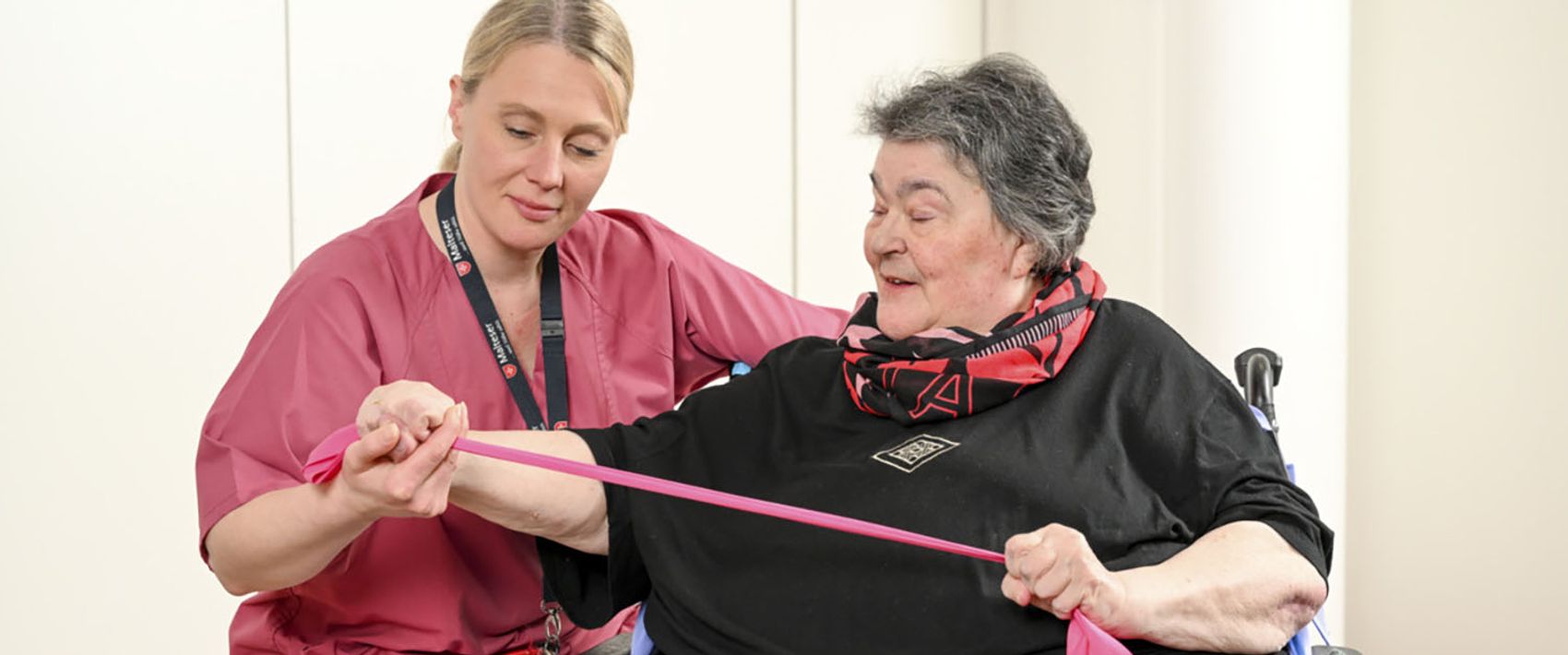 Eine Pflegerin mit einer Patientin beim Training mit einem Terraband