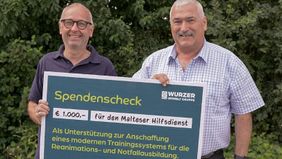 Tobias Cako und Edwin Lambert halten gemeinsam einen symbolischen Spendenscheck.