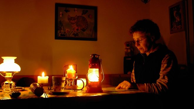 Eine Frau liest beim Schein von Kerzen und Laternen