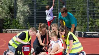 Malteser Schulsanitäter versorgen ein Mädchen, das sich beim Sport verletzt hat.