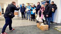 Freiwillige der Malteser übergeben Taschen an die Bahnhofsmission Halle. Dabei werden sie fotografiert.