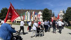 Menschen mit und ohne Rollstuhl oder Rollator auf dem Weg zur Basilika in Altötting