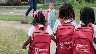 Schulmädchen mit einem Malteser Rucksack