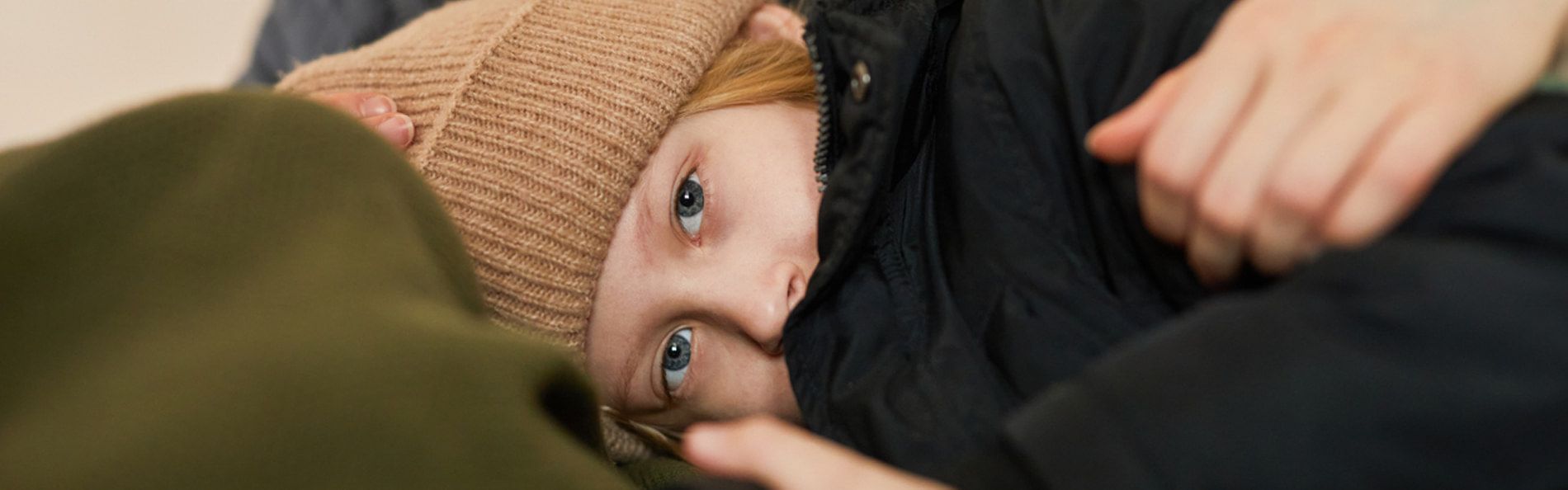 Ein Kind in Winterkleidung liegt auf dem Schoß einer Frau