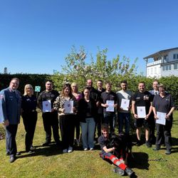 Die Helferinnen und Helfer der Malteser sowie eine Vertreterin des Lahn-Dill-Kreis und ein Hund des Besuchsdienstes stehen im Freien. Einige Personen halten Urkunden in der Hand.